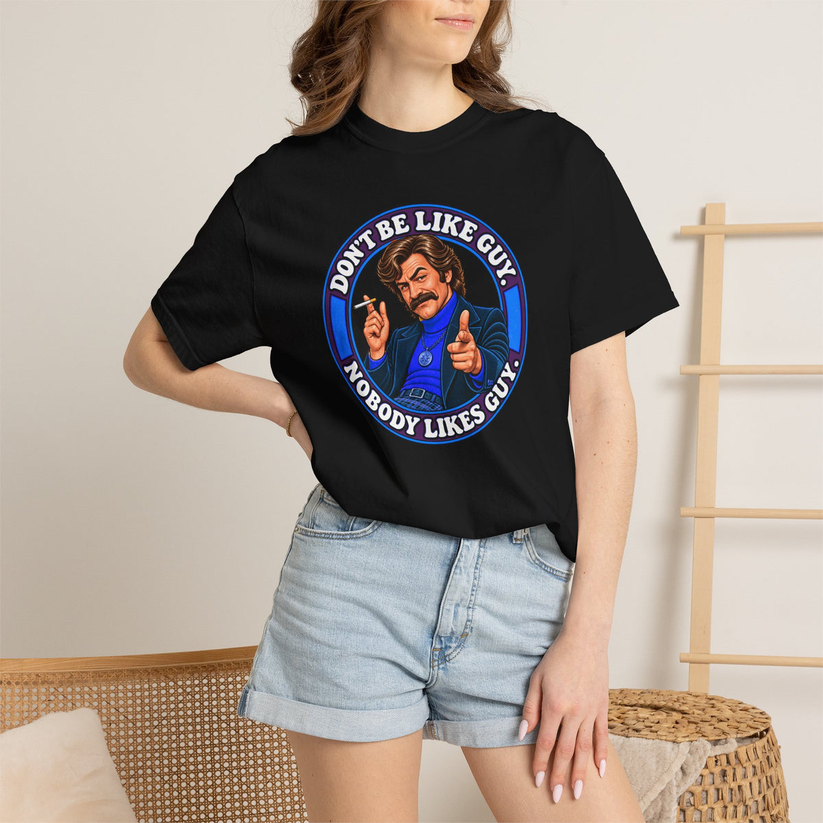 Woman wearing black Don’t Be Like Guy t-shirt and denim shorts